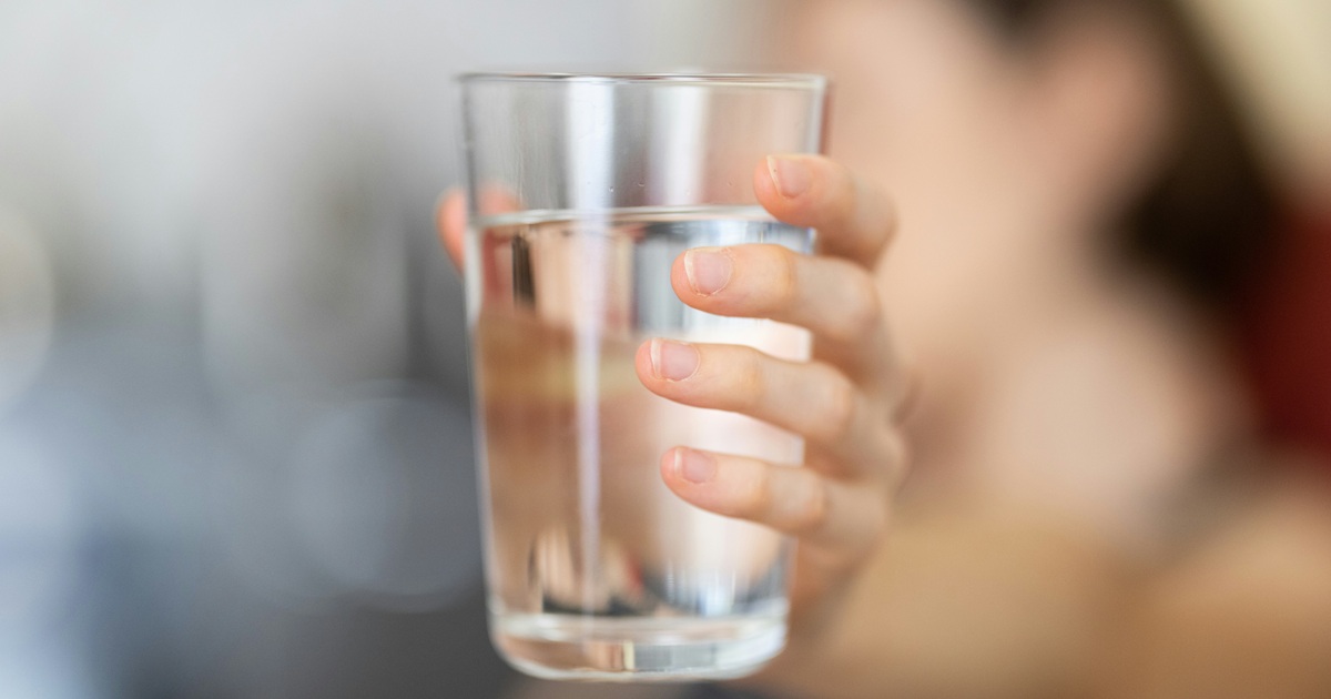 透明なグラスに入った水を手で持つ様子