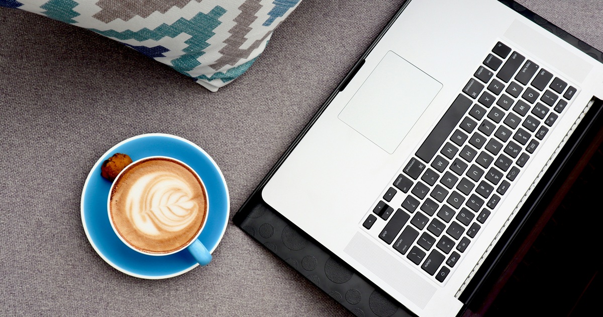 在宅ワーク中のデスクにラテアートのコーヒーカップとノートパソコンが置かれた様子